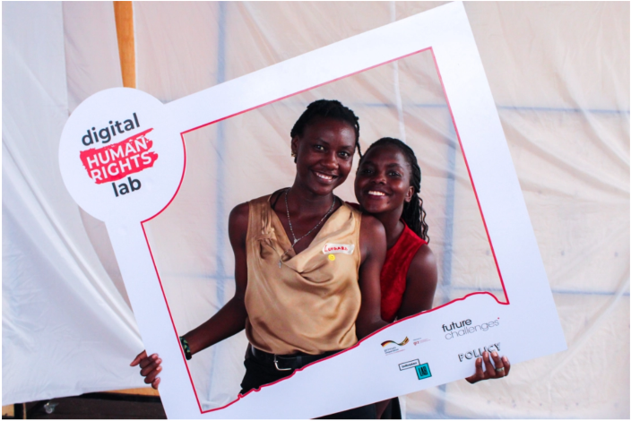 Two women holding a picture frame around themselves with the DHRLab logo